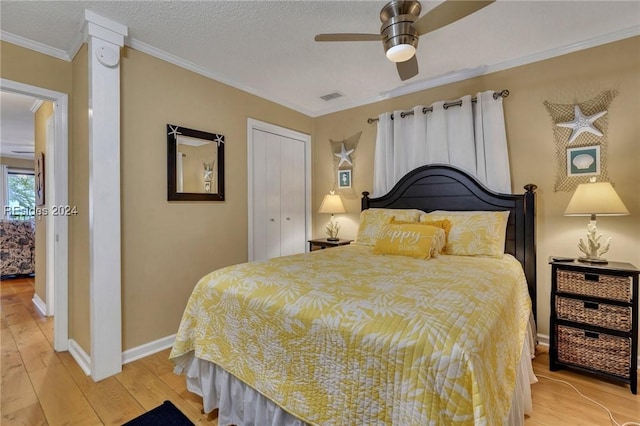 bedroom with crown molding, a textured ceiling, a closet, ceiling fan, and light hardwood / wood-style floors