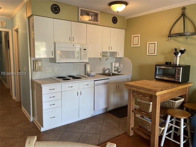 kitchen featuring sink, white appliances, tasteful backsplash, ornamental molding, and white cabinets