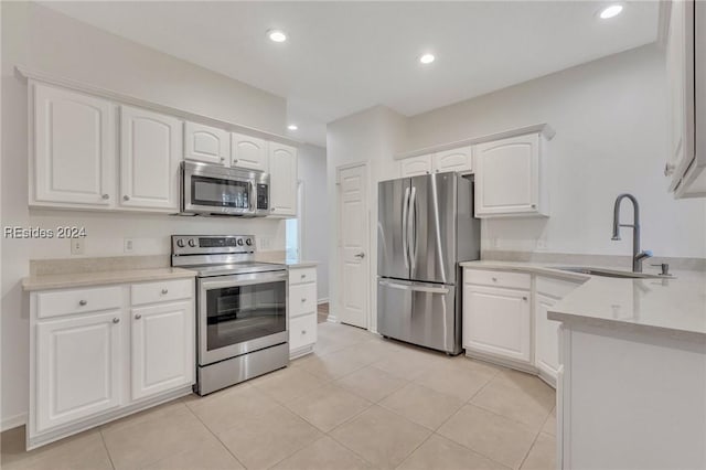 kitchen featuring sink, light tile patterned floors, stainless steel appliances, and white cabinets