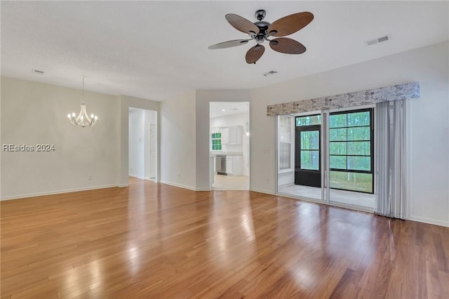 spare room featuring wood-type flooring and ceiling fan with notable chandelier