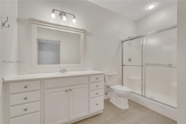 bathroom with a shower with shower door, vanity, toilet, tile patterned floors, and a textured ceiling