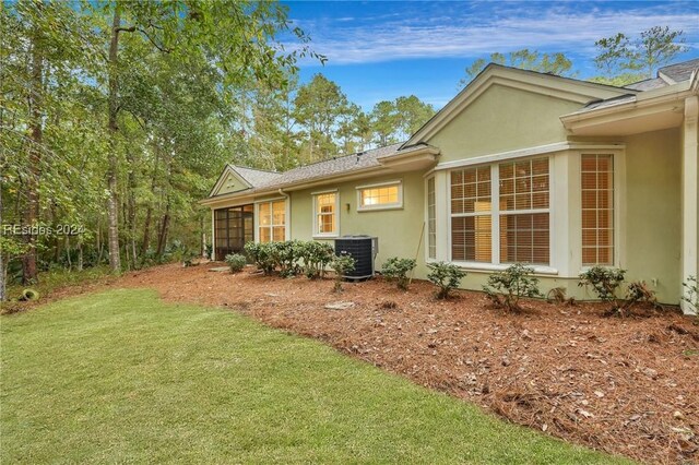 view of side of home featuring cooling unit and a lawn