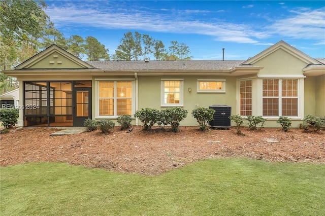 rear view of property with central AC unit, a lawn, and a sunroom