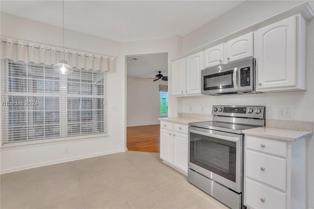 kitchen featuring stainless steel appliances, pendant lighting, light tile patterned floors, and white cabinets