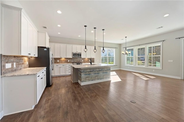 kitchen featuring sink, white cabinetry, appliances with stainless steel finishes, pendant lighting, and a kitchen island with sink