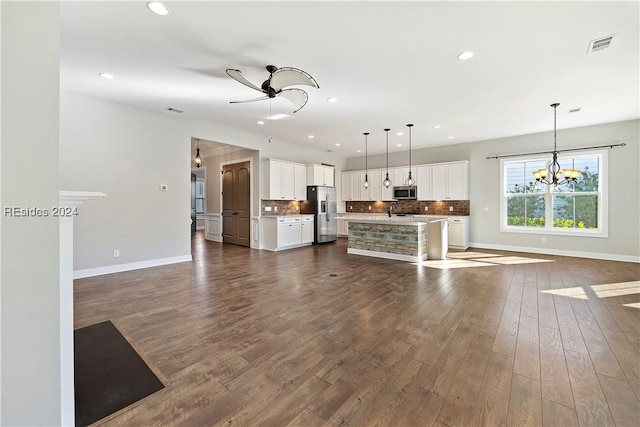 kitchen featuring stainless steel appliances, white cabinetry, an island with sink, and decorative light fixtures