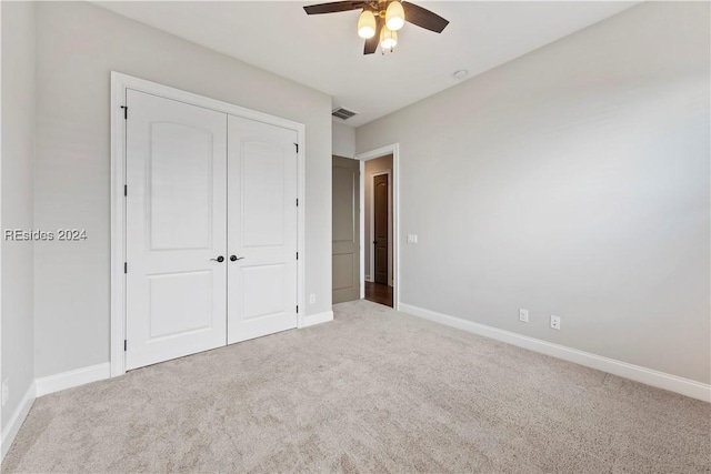 unfurnished bedroom with ceiling fan, light carpet, and a closet