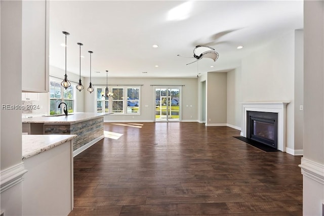 unfurnished living room featuring dark hardwood / wood-style flooring, sink, and a notable chandelier