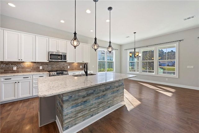 kitchen featuring stainless steel appliances, an island with sink, and white cabinets