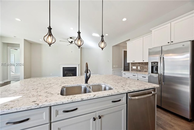 kitchen with sink, hanging light fixtures, stainless steel appliances, white cabinets, and decorative backsplash