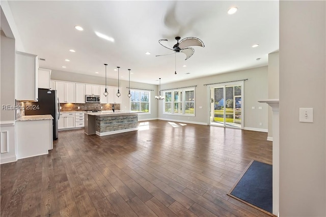 kitchen featuring ceiling fan, a kitchen island with sink, tasteful backsplash, white cabinets, and decorative light fixtures