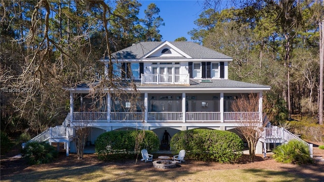 view of front of home with a balcony, an outdoor fire pit, a sunroom, and a front yard