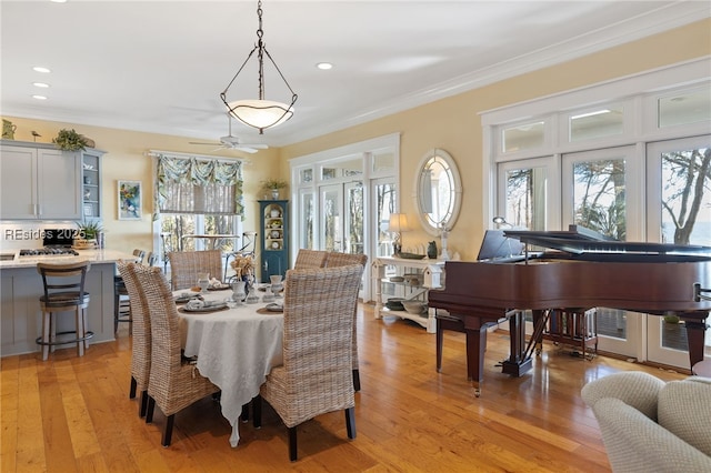 dining area featuring ceiling fan, ornamental molding, and light wood-type flooring