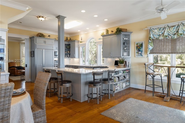 kitchen featuring decorative columns, gray cabinetry, dark hardwood / wood-style flooring, and kitchen peninsula