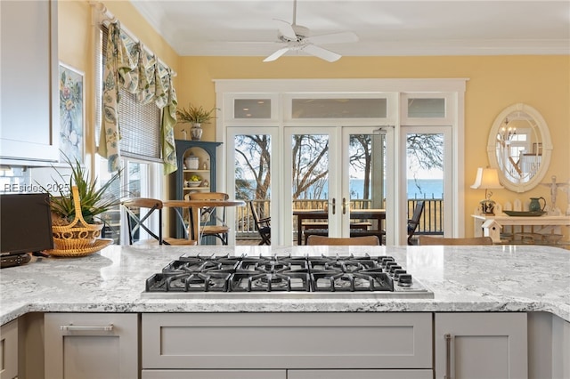 kitchen featuring gray cabinets, ornamental molding, stainless steel gas cooktop, and light stone counters