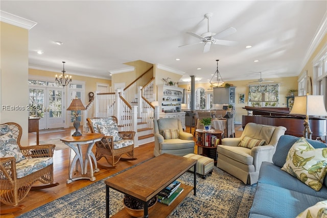 living room with ornate columns, crown molding, wood-type flooring, and ceiling fan with notable chandelier