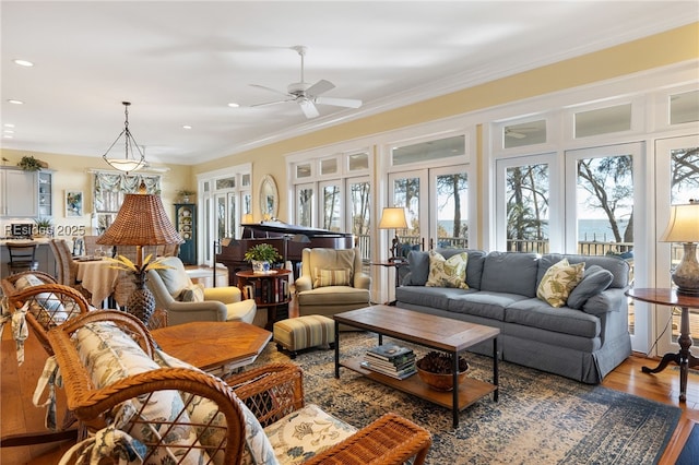 living room with hardwood / wood-style flooring, ornamental molding, and ceiling fan