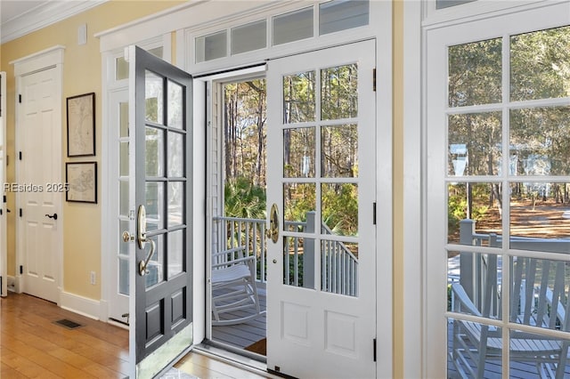 entryway featuring crown molding, a healthy amount of sunlight, and light wood-type flooring