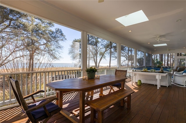 sunroom featuring a water view, ceiling fan, a skylight, and a wealth of natural light