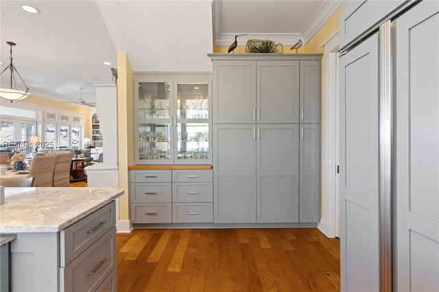 interior space featuring gray cabinetry, decorative light fixtures, ornamental molding, and light hardwood / wood-style floors