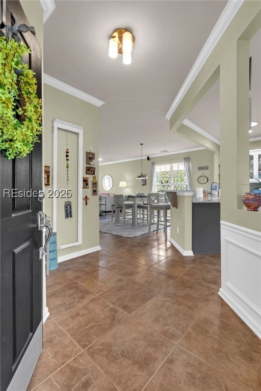 foyer entrance with ornamental molding and dark tile patterned floors