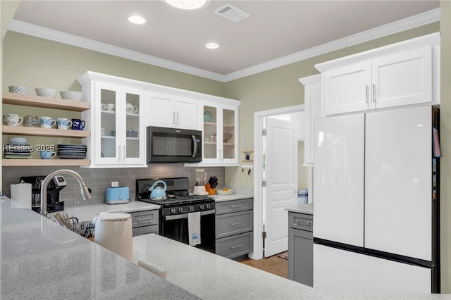 kitchen featuring gray cabinetry, stainless steel gas range oven, white cabinets, and white refrigerator