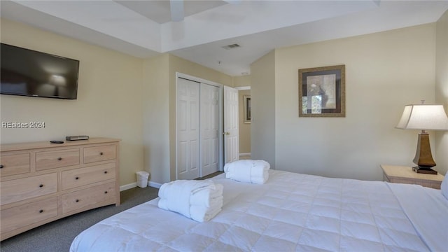 bedroom featuring a tray ceiling, a closet, and dark colored carpet