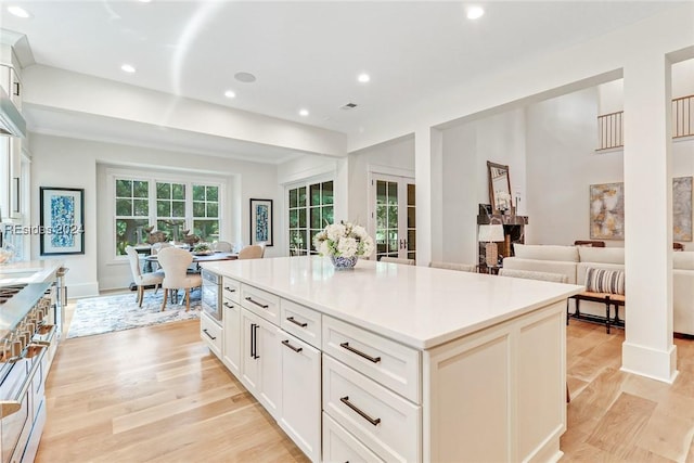 kitchen featuring a center island, white cabinets, light wood-type flooring, and french doors