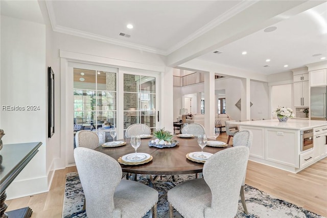 dining space with ornamental molding and light hardwood / wood-style flooring