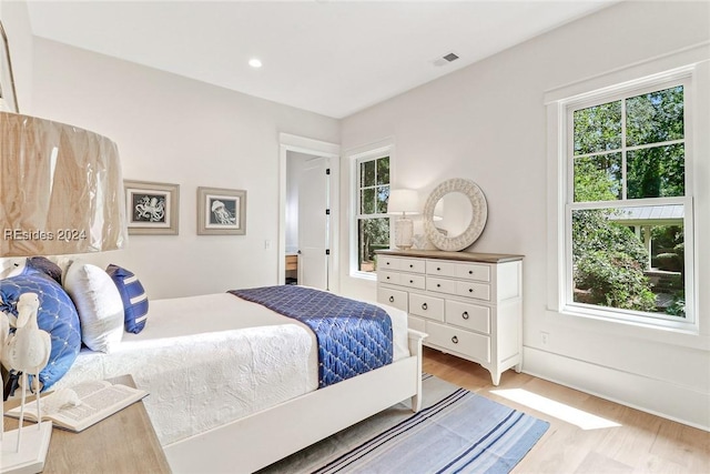 bedroom with multiple windows and light hardwood / wood-style flooring