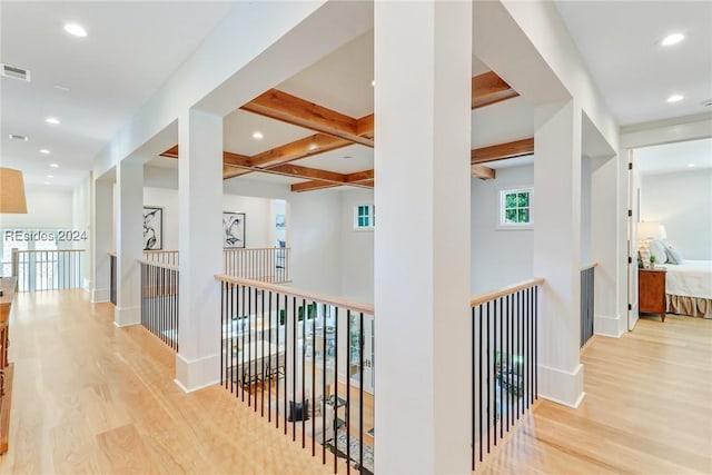 corridor with coffered ceiling, beam ceiling, and light wood-type flooring