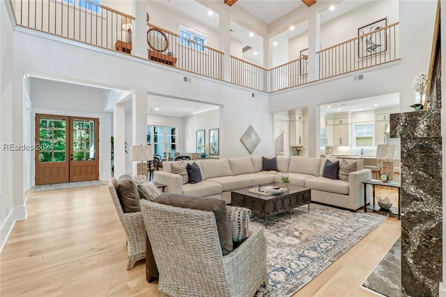 living room featuring french doors, light hardwood / wood-style floors, and a high ceiling