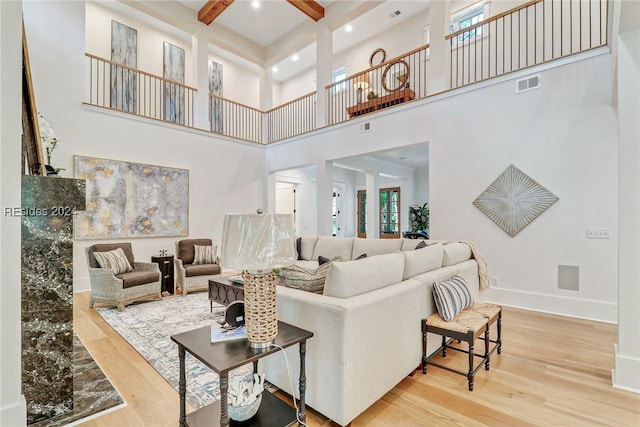 living room with beamed ceiling, hardwood / wood-style floors, and a high ceiling