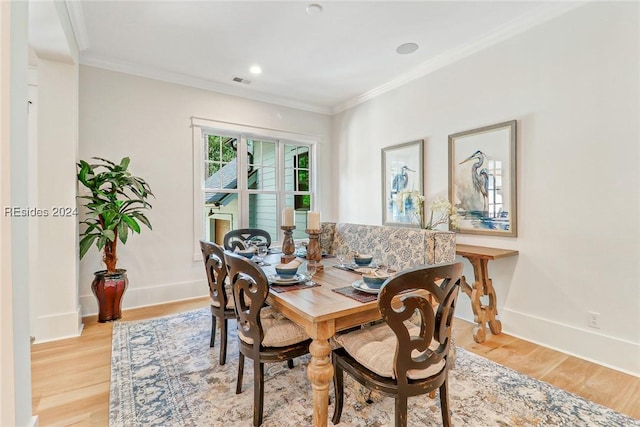 dining space with crown molding and light hardwood / wood-style flooring