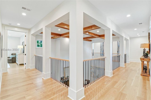 hall featuring coffered ceiling, beam ceiling, and light hardwood / wood-style flooring