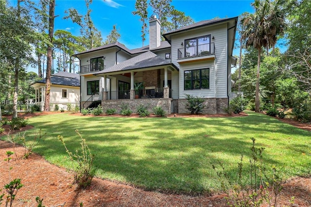 rear view of house with a balcony and a lawn