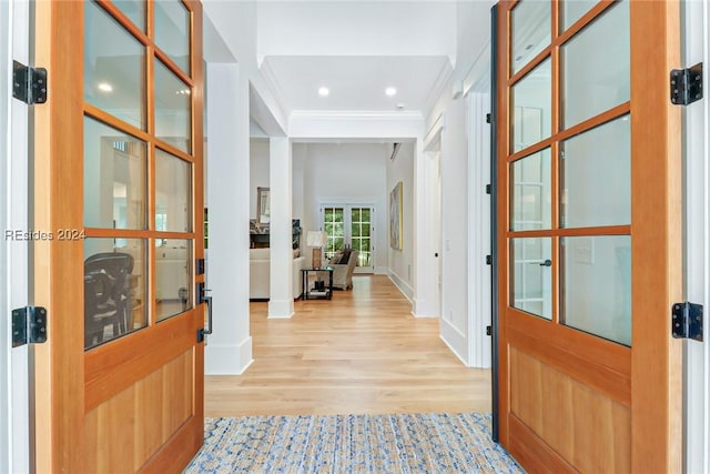 foyer entrance with crown molding and light hardwood / wood-style flooring