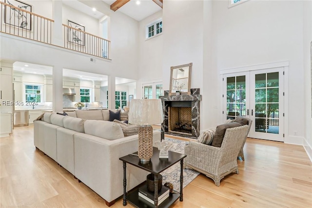 living room with french doors, a towering ceiling, and light hardwood / wood-style flooring