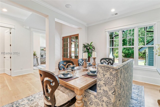 dining space featuring crown molding, a wealth of natural light, light wood-type flooring, and french doors