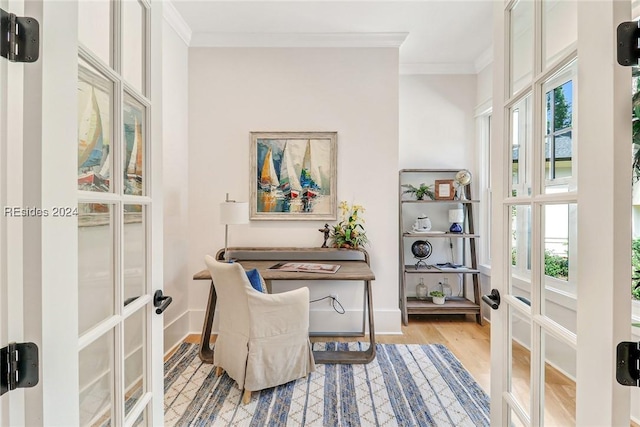 office with ornamental molding, a healthy amount of sunlight, light hardwood / wood-style flooring, and french doors