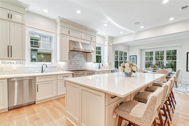 kitchen featuring a kitchen island, tasteful backsplash, dishwasher, exhaust hood, and light hardwood / wood-style floors