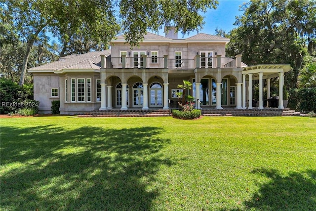 rear view of house featuring a balcony, a porch, and a lawn