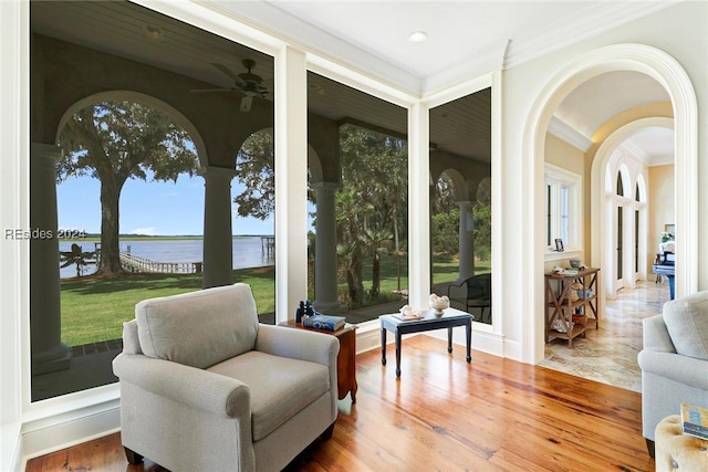 sitting room with a water view, ornamental molding, and hardwood / wood-style floors