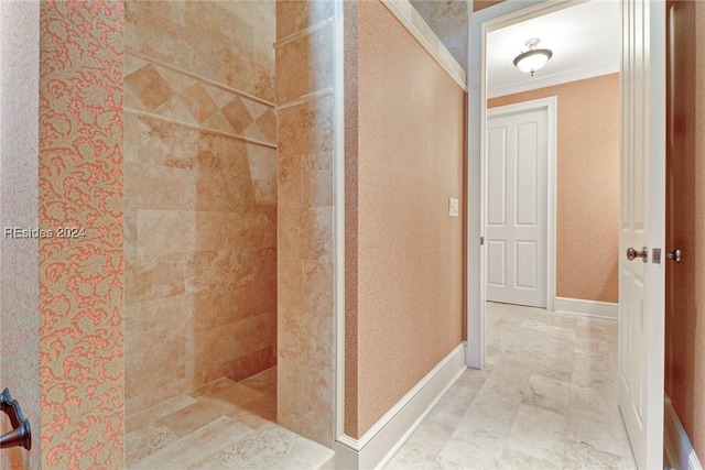 bathroom with ornamental molding and tiled shower