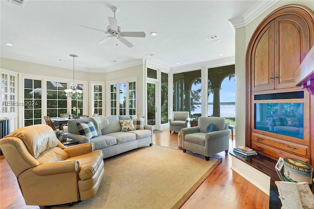 living room featuring ceiling fan with notable chandelier, ornamental molding, and light hardwood / wood-style floors