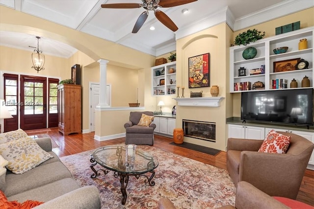 living room featuring ceiling fan, ornamental molding, light hardwood / wood-style floors, and decorative columns