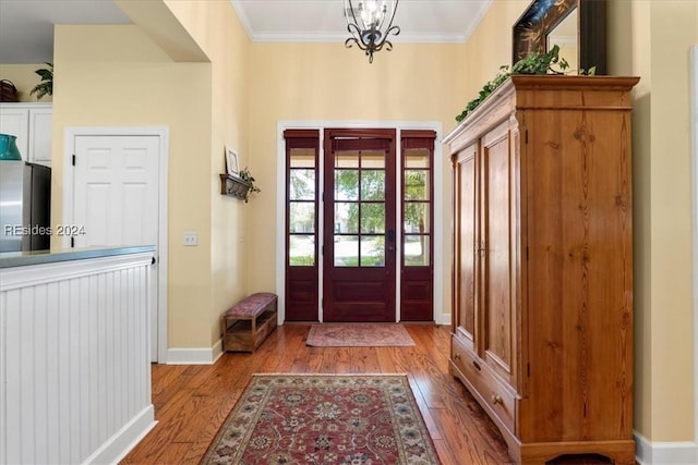 entryway featuring crown molding, hardwood / wood-style floors, and a chandelier