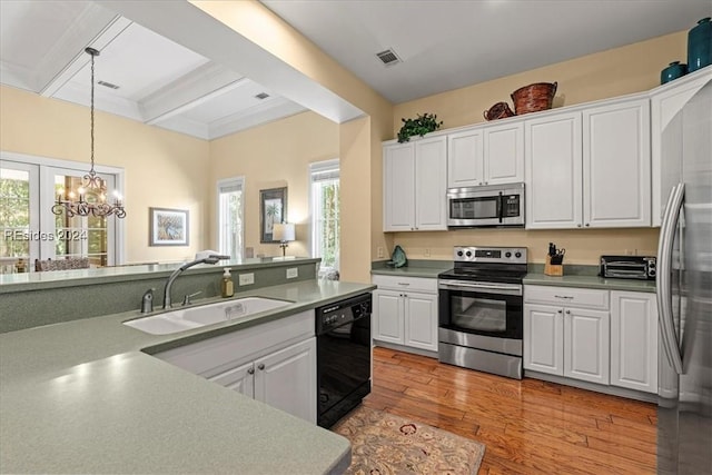 kitchen with pendant lighting, sink, appliances with stainless steel finishes, white cabinets, and light wood-type flooring