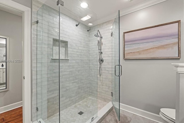 bathroom featuring tile patterned flooring, crown molding, a shower with door, and toilet