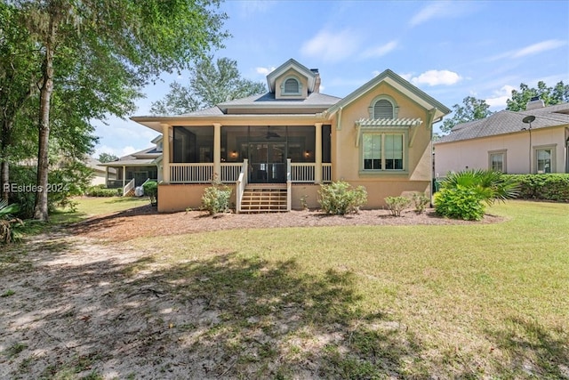 back of property with a sunroom, ceiling fan, and a lawn